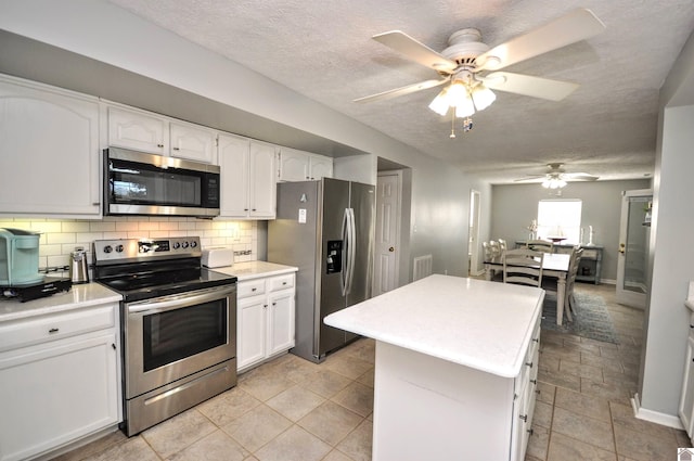 kitchen featuring a kitchen island, backsplash, white cabinets, appliances with stainless steel finishes, and a textured ceiling