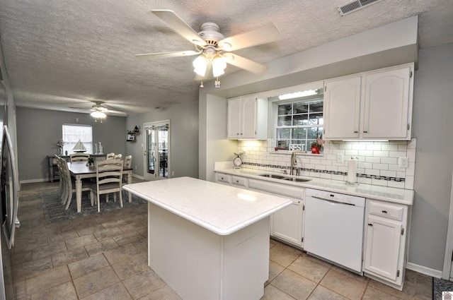 kitchen with a kitchen island, decorative backsplash, white dishwasher, sink, and white cabinetry