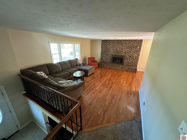 living room featuring wood-type flooring, a textured ceiling, and a fireplace