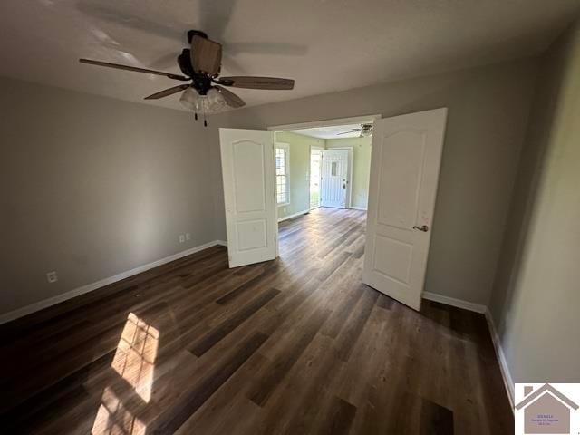 empty room with ceiling fan and dark hardwood / wood-style flooring