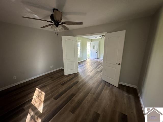 spare room with baseboards, a ceiling fan, and dark wood-type flooring