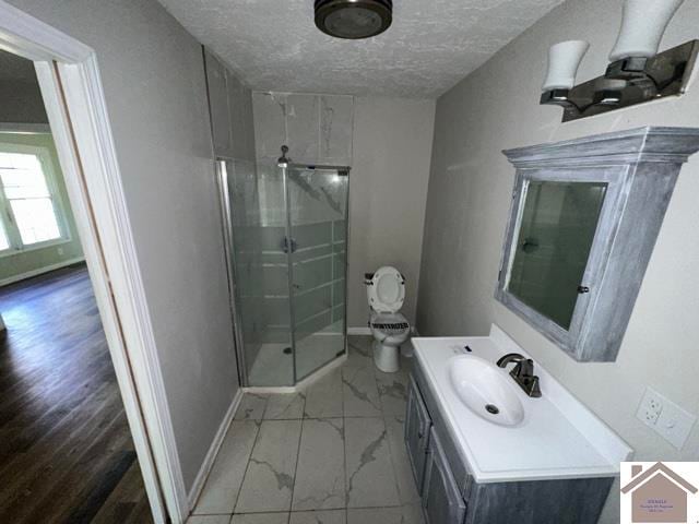 bathroom with a textured ceiling, walk in shower, wood-type flooring, toilet, and vanity