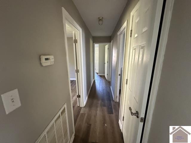 corridor with baseboards, visible vents, and dark wood-style floors