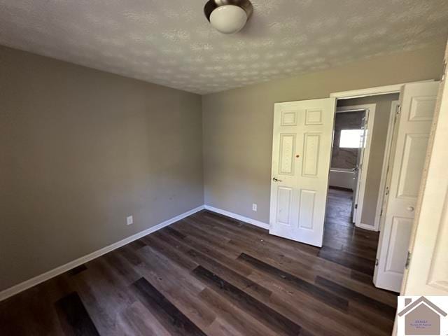 empty room featuring a textured ceiling and dark hardwood / wood-style flooring