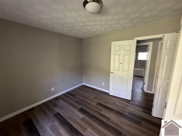 unfurnished room featuring baseboards, a textured ceiling, and dark wood-style floors