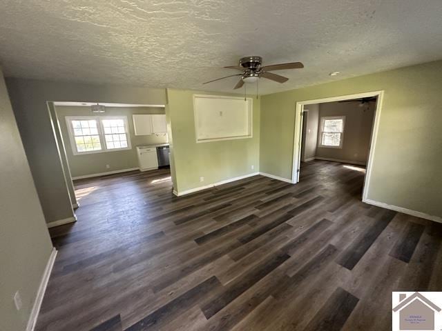 unfurnished living room featuring a textured ceiling, a ceiling fan, baseboards, and dark wood-style floors