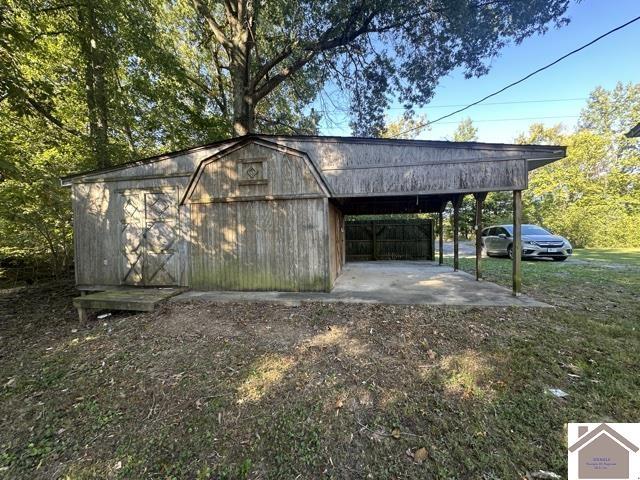 view of outbuilding with an outdoor structure, a carport, and dirt driveway