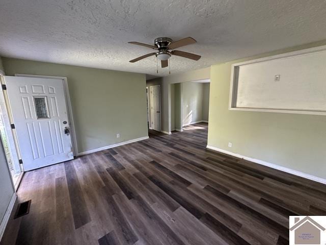 unfurnished living room with baseboards, dark wood-style floors, a textured ceiling, and ceiling fan