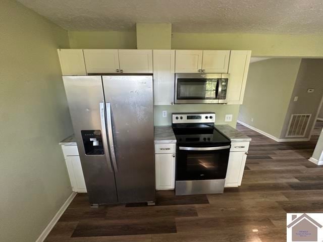 kitchen with white cabinetry, stainless steel appliances, and dark hardwood / wood-style floors