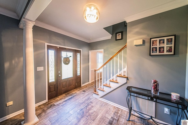 foyer featuring ornamental molding, ornate columns, wood-type flooring, and an inviting chandelier