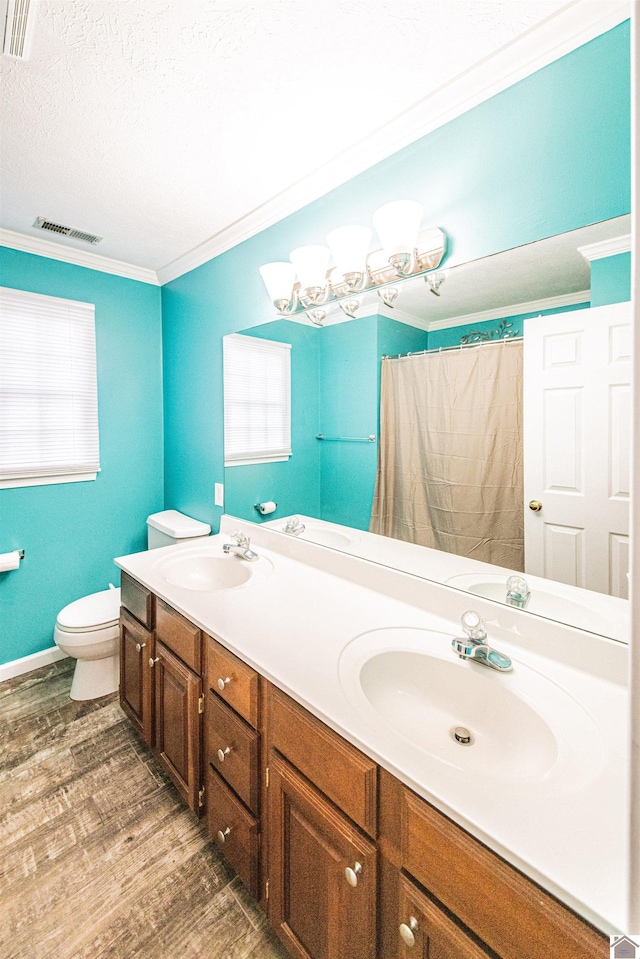 bathroom with a textured ceiling, hardwood / wood-style flooring, toilet, vanity, and crown molding