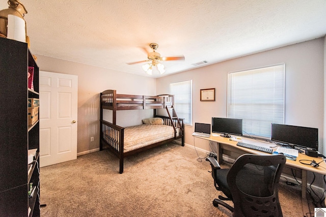 bedroom featuring a textured ceiling, light colored carpet, and ceiling fan