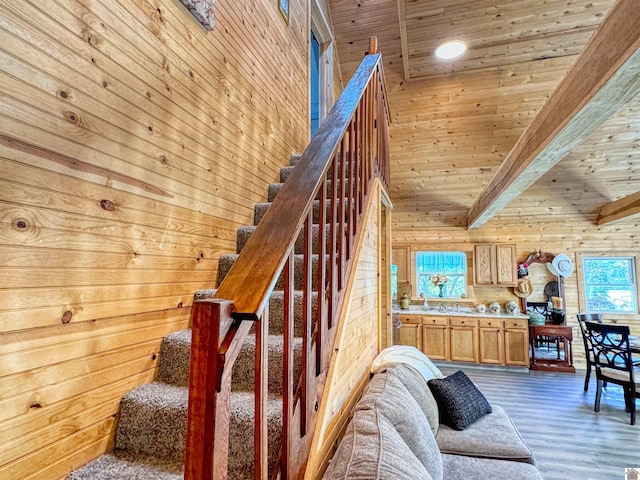 staircase featuring beam ceiling, hardwood / wood-style flooring, wooden ceiling, and wood walls