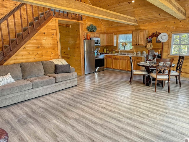 living room featuring light wood-type flooring, a healthy amount of sunlight, and wood walls