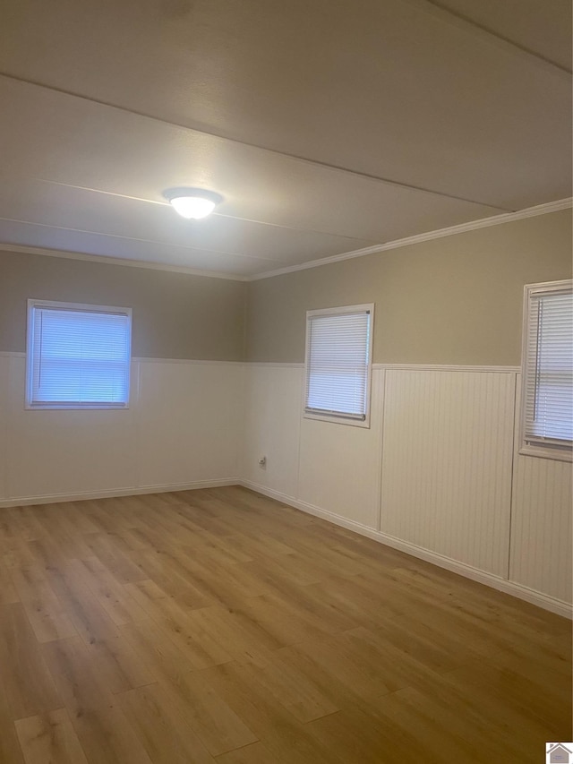 spare room with a wealth of natural light, ornamental molding, and wood-type flooring