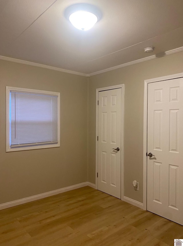 unfurnished bedroom featuring crown molding and light wood-type flooring