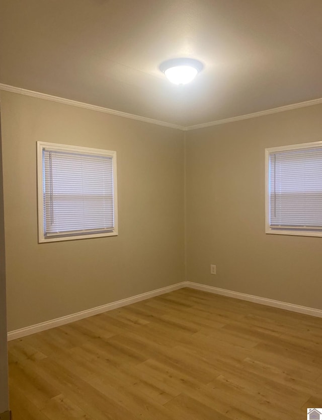 empty room with crown molding and light hardwood / wood-style flooring