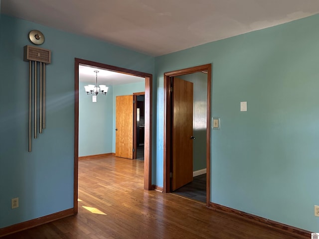 spare room featuring hardwood / wood-style flooring and an inviting chandelier