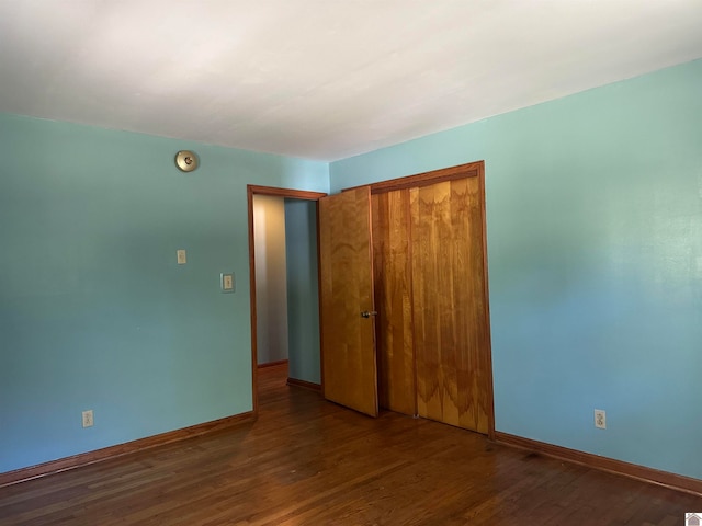 unfurnished bedroom featuring a closet and dark hardwood / wood-style flooring