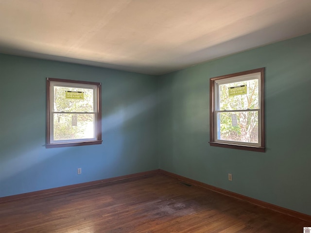 spare room with dark hardwood / wood-style floors and plenty of natural light