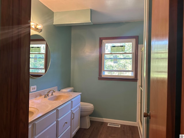 bathroom featuring toilet, a healthy amount of sunlight, vanity, and hardwood / wood-style flooring