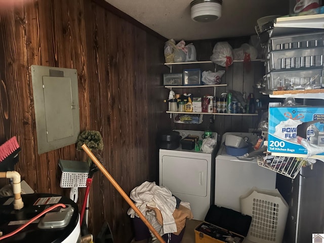 clothes washing area featuring electric panel, independent washer and dryer, and wood walls