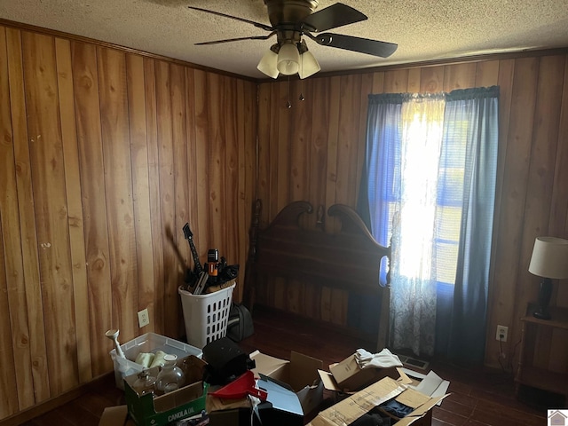 misc room with dark wood-type flooring, ceiling fan, wood walls, and a textured ceiling