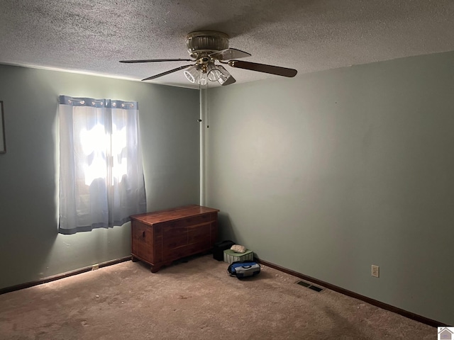 empty room featuring a textured ceiling, light colored carpet, and ceiling fan