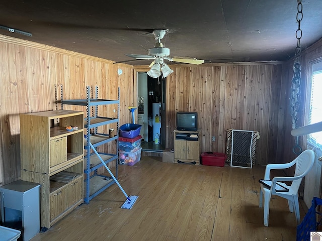 basement with crown molding, wood walls, wood-type flooring, and ceiling fan