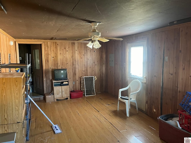 misc room with hardwood / wood-style flooring, wooden walls, and ceiling fan