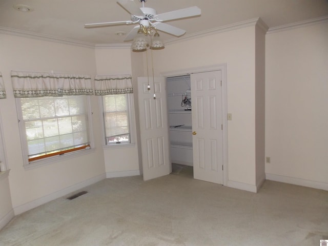 unfurnished bedroom featuring ceiling fan, crown molding, and light colored carpet