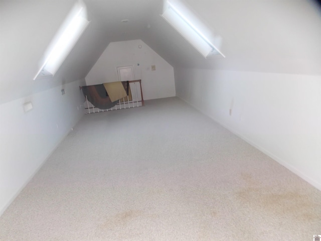 additional living space with lofted ceiling with skylight and carpet flooring