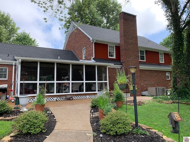 back of property with central air condition unit, a yard, and a sunroom