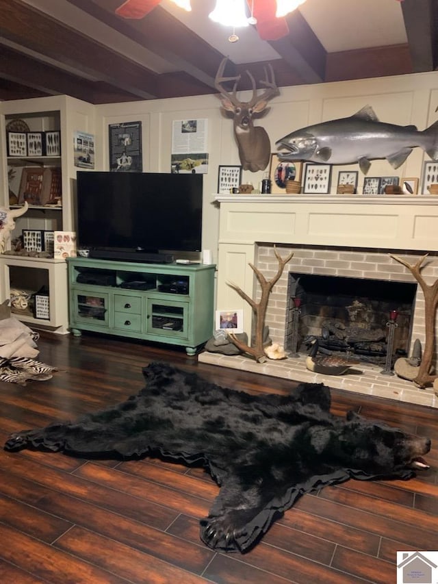 living room with dark hardwood / wood-style floors, beam ceiling, and a brick fireplace