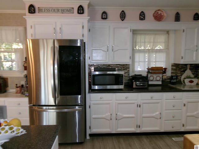 kitchen featuring decorative backsplash, hardwood / wood-style floors, appliances with stainless steel finishes, white cabinetry, and crown molding