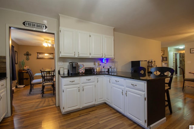 kitchen featuring hardwood / wood-style floors, white cabinets, kitchen peninsula, and ceiling fan