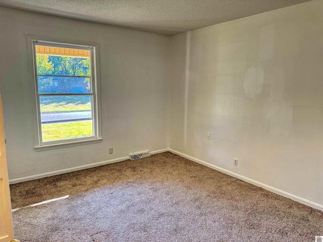 carpeted empty room with a textured ceiling