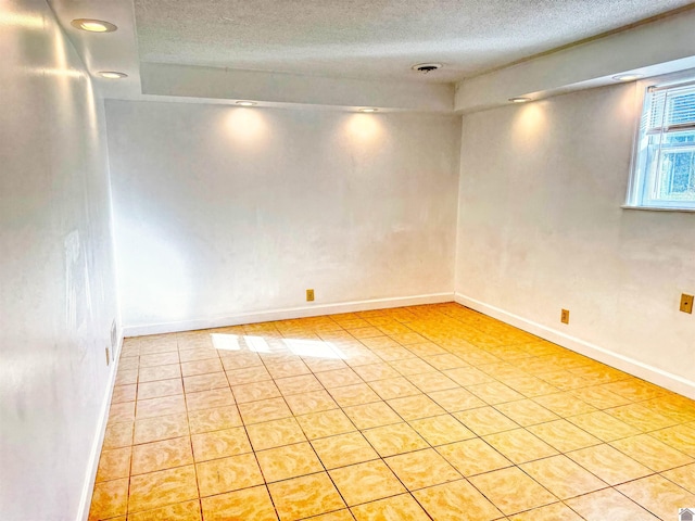 tiled empty room with a textured ceiling