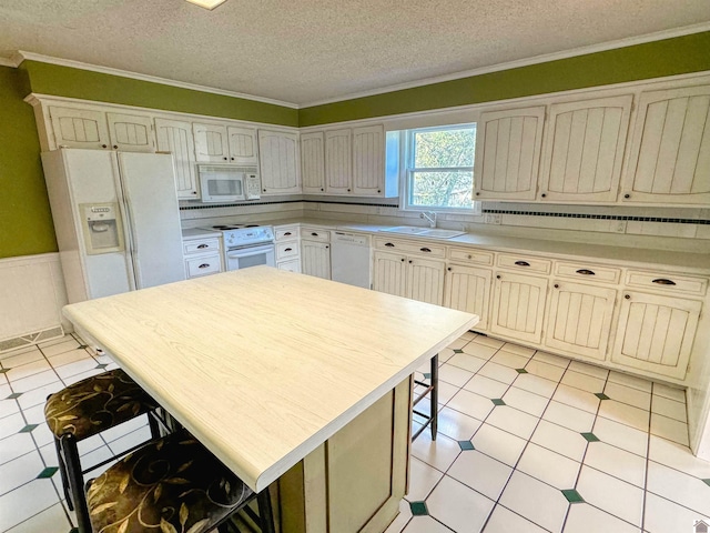 kitchen with sink, crown molding, a textured ceiling, and white appliances