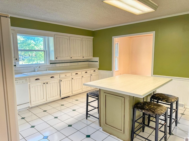1516 Canterbury Dr, Murray, KY 42071 - kitchen with a sink, white dishwasher, a breakfast bar, wainscoting, and light countertops