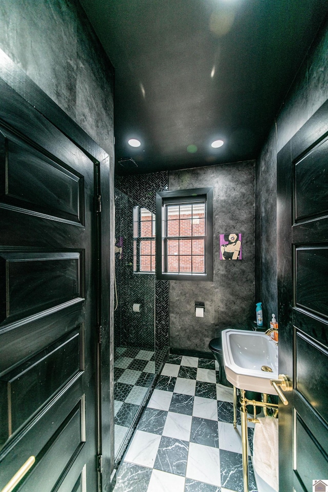 bathroom featuring toilet, sink, and a tile shower