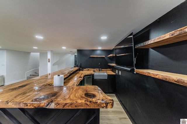 kitchen featuring butcher block counters, sink, kitchen peninsula, and light hardwood / wood-style floors