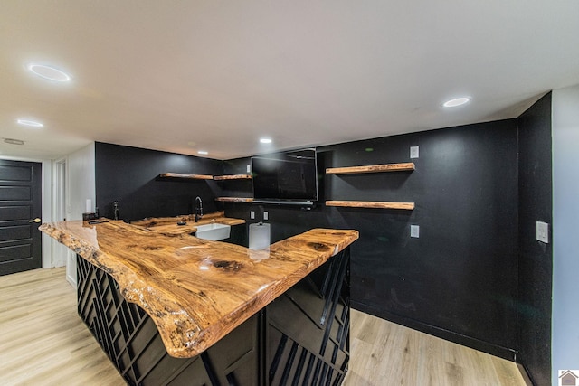 kitchen with sink, butcher block countertops, and light wood-type flooring