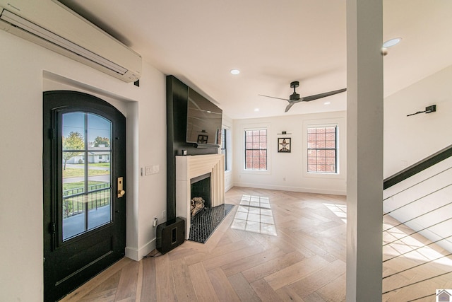 unfurnished living room with a wall mounted air conditioner, light parquet floors, and ceiling fan