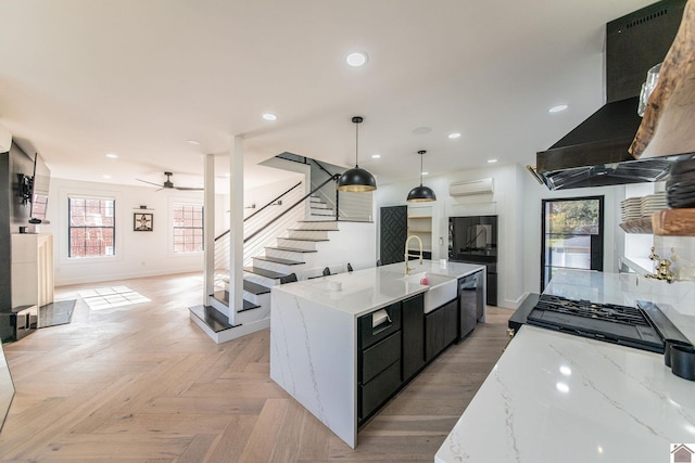 kitchen featuring exhaust hood, a large island with sink, sink, pendant lighting, and light parquet floors