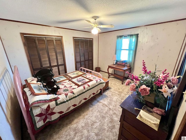 bedroom with a textured ceiling, multiple closets, carpet, and ceiling fan