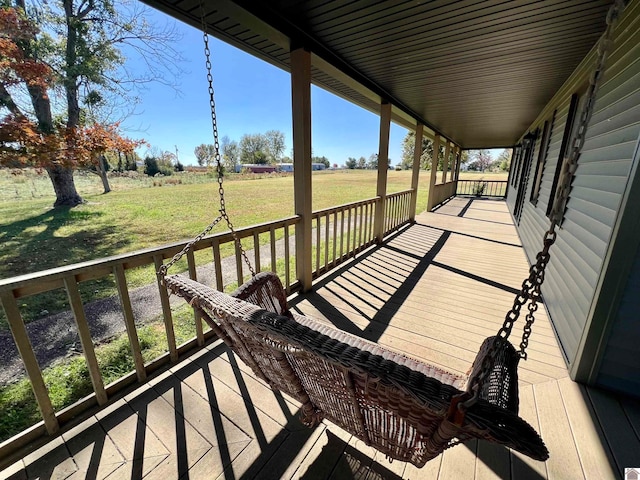 wooden terrace with a yard and a rural view