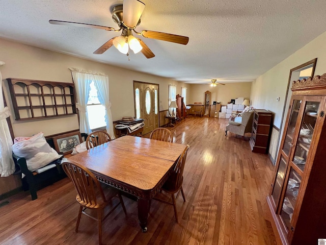 dining space featuring a textured ceiling, hardwood / wood-style flooring, and ceiling fan