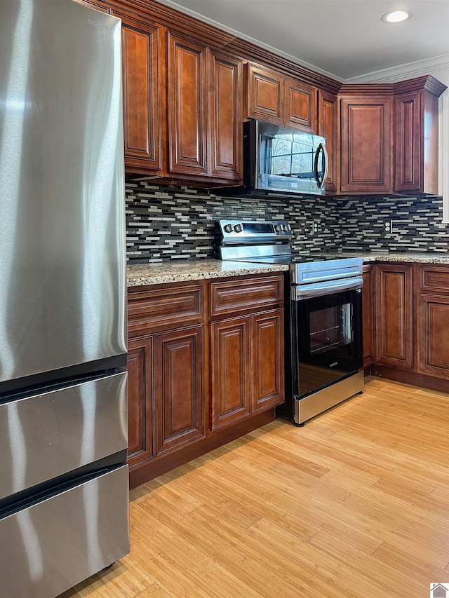 kitchen with light stone counters, decorative backsplash, stainless steel appliances, and light wood-type flooring