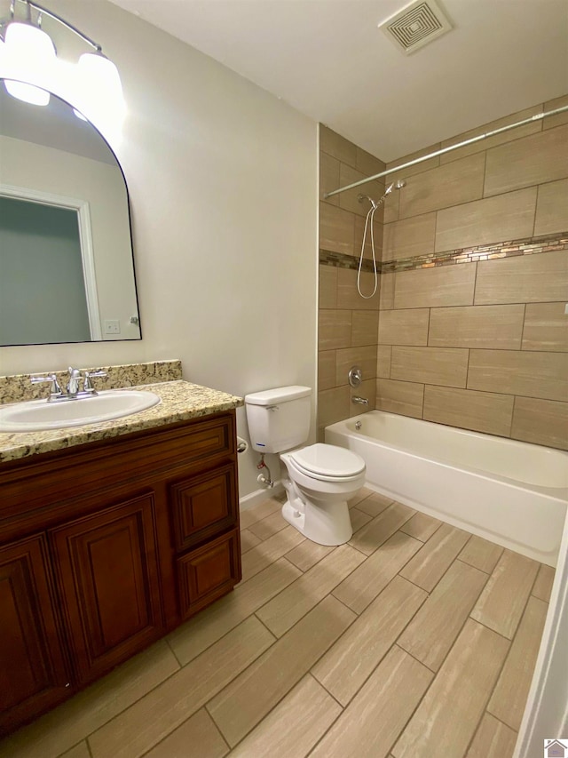 full bathroom featuring toilet, tiled shower / bath combo, and vanity